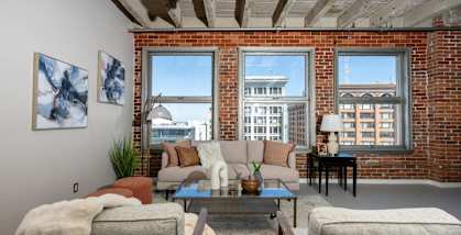 a living room with couches and a table and a brick wall