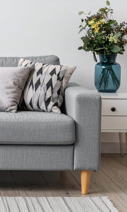 A grey couch with a white knitted throw draped over the left side.