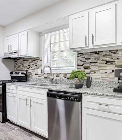 a kitchen with white cabinets and a counter top at Elea Apartments in Marietta, GA