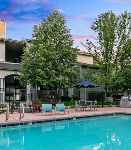 a pool with chairs and umbrellas near a building with a resort style pool at Ascent Apartments, Cottonwood Heights, UT