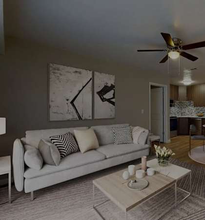 A modern living room with a grey sofa, a coffee table, and a ceiling fan.