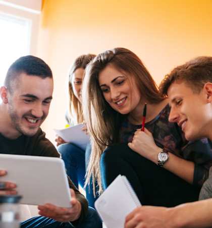 a group of people sitting on a couch looking at a tablet computer