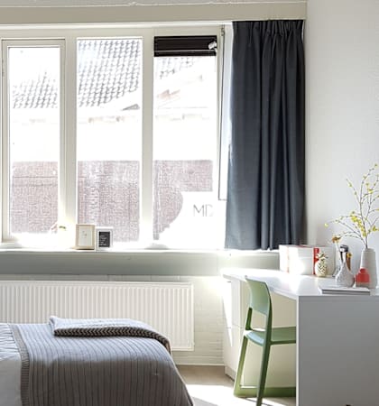 A bedroom with a bed, a chair, and a window.