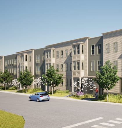 A blue car is driving down a street past apartment buildings.