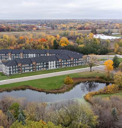 an aerial view of a building next to a pond