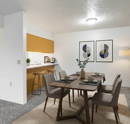 A dining room with a table set for two and a kitchen area in the background.