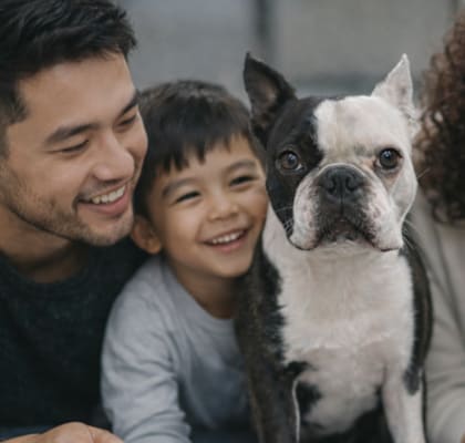 A family with a dog is smiling and looking at the camera.