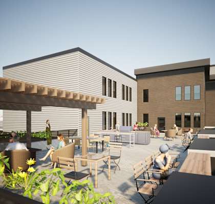 A modern building with a rooftop patio with people sitting and enjoying the day.
