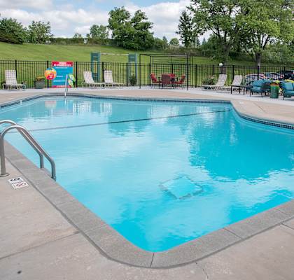 a swimming pool with chaise lounge chairs and trees in the background