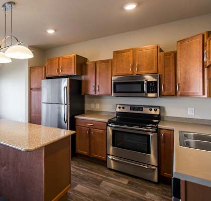 an empty kitchen with wooden cabinets and stainless steel appliances