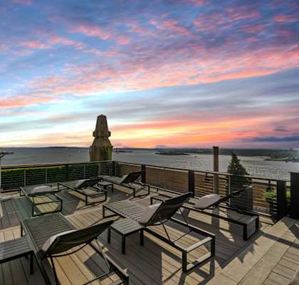 A rooftop patio with a table and chairs overlooking the water. at One West,  New York,10004