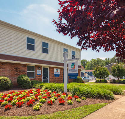 A building with a sign in front of it and a flower bed in the front.