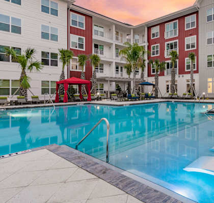 A large swimming pool in front of a red and white building.