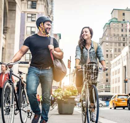 A man and a woman are riding bicycles on a city street.