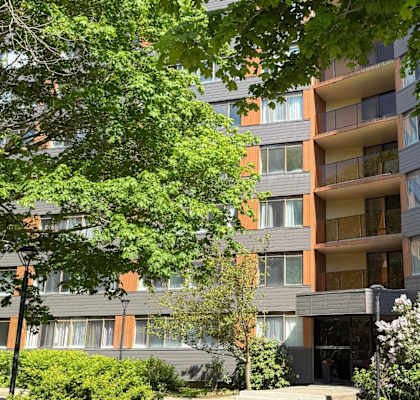 A modern apartment building with balconies and surrounded by greenery.