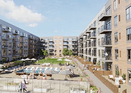 A sunny day at a modern apartment complex with people walking and lounging in the courtyard.