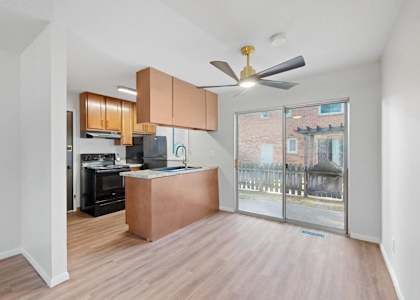 A modern kitchen with a wooden island and a ceiling fan.