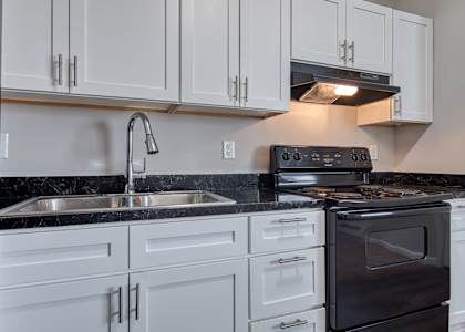 A modern kitchen with white cabinets and black countertops.