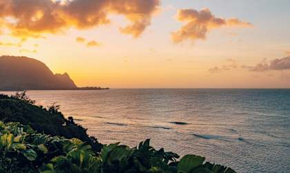 a sunset over the ocean with a view of a beach and