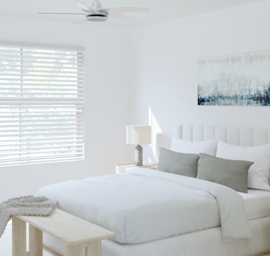 A white bedroom with a bed, nightstand, and a painting on the wall.