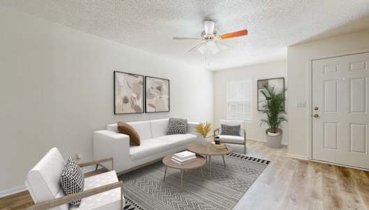 A living room with a white couch, a wooden coffee table, and a ceiling fan.