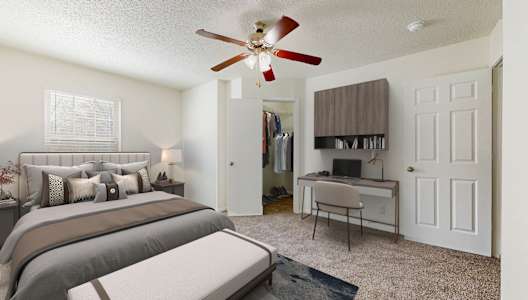A bedroom with a bed, desk, and a ceiling fan.