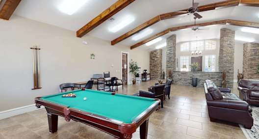 A pool table is in the middle of a room with a stone fireplace.