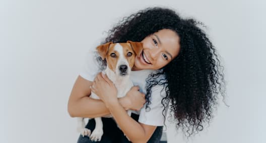 A woman with curly hair is holding a small dog.