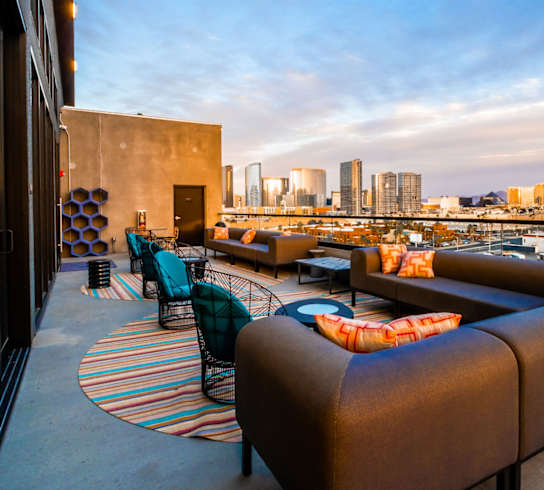 A rooftop patio with a view of the city skyline at dusk.