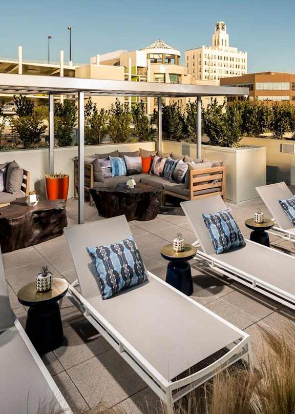 A rooftop patio with lounge chairs and cushions overlooking a cityscape.at Chelsea Santa Monica, Santa Monica, CA 90411