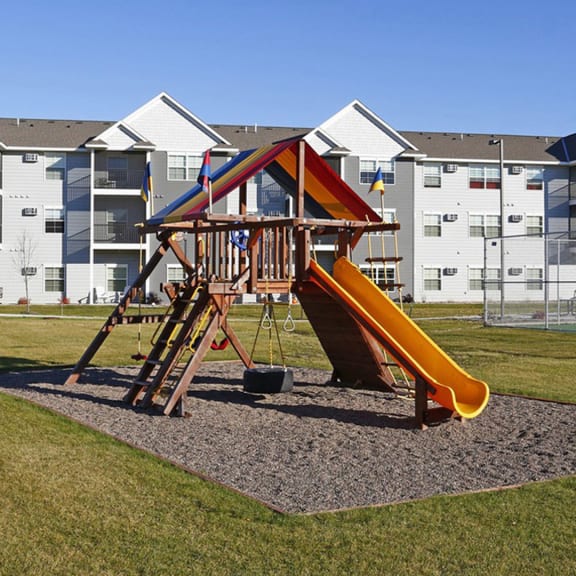a playground with a slide in front of an apartment building