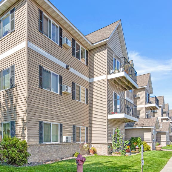 an apartment building with tan siding and a sidewalk in front of it
