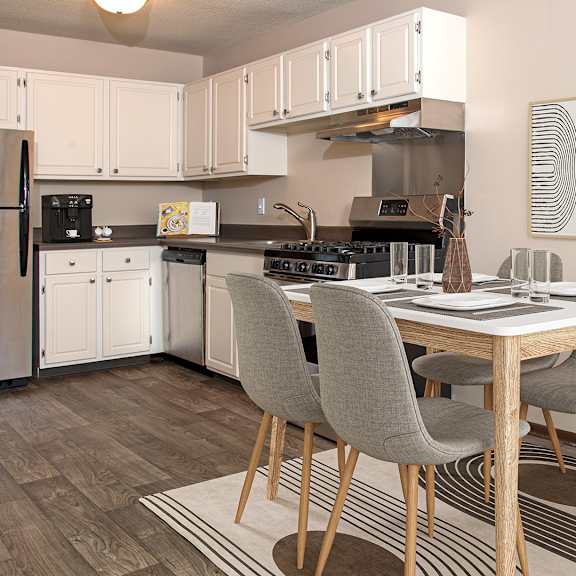 A kitchen with a dining table and chairs.