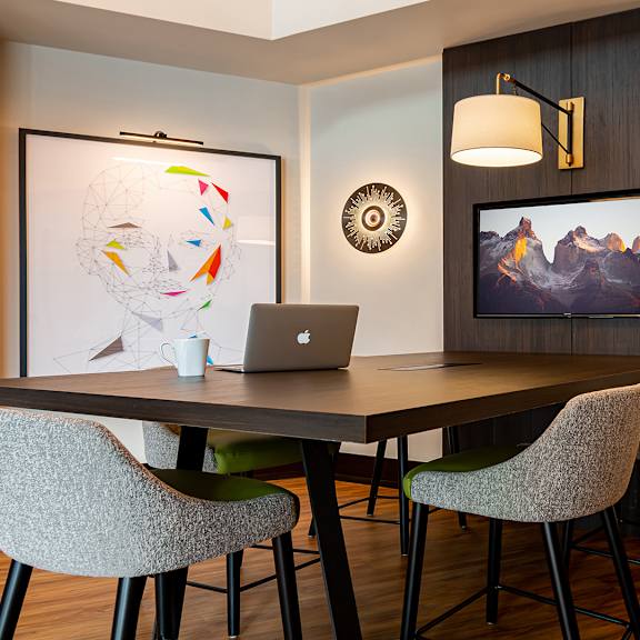 a conference room with a laptop on a table and a painting on the wall