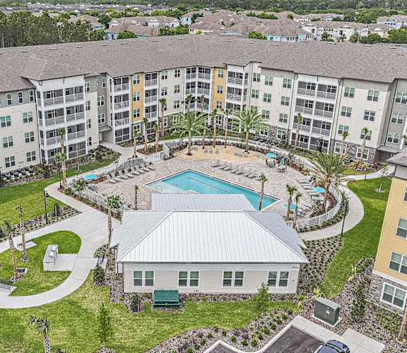 A large apartment complex with a pool and a small house.