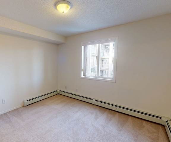 A large, empty carpeted bedroom with overhead lighting and a window at Somerset Pointe Apartment Homes. 