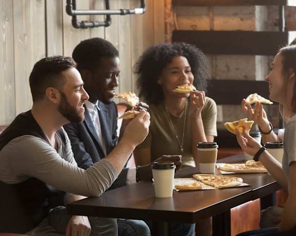 group of people eating pizza at a restaurant
