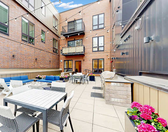 A patio with a table and chairs is surrounded by brick buildings.