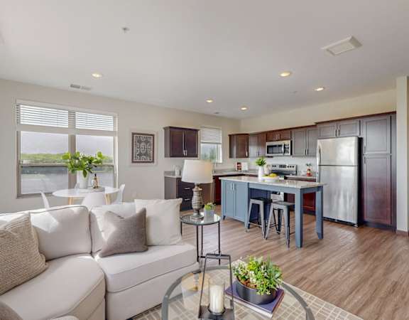 A modern living room with a white couch and a kitchen in the background.