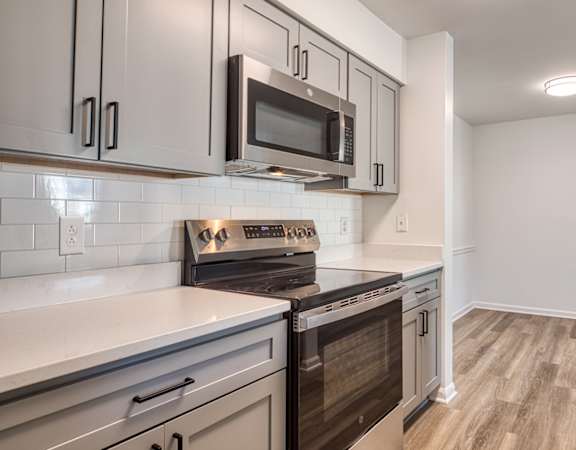 A kitchen with a black stove top oven and a black microwave above it.