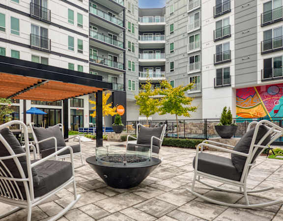 A patio with a fire pit and chairs.