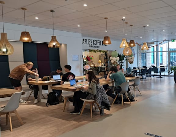 A group of people are sitting at tables in a large open space.