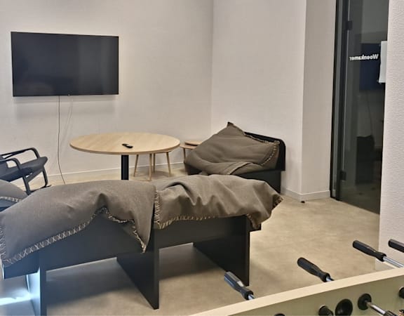 A modern lounge area with a television, chairs, and a table.