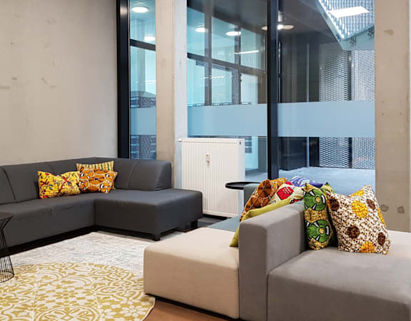 A grey couch with yellow pillows sits in a room with a large window.