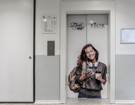A woman is standing in a doorway with a phone in her hand.