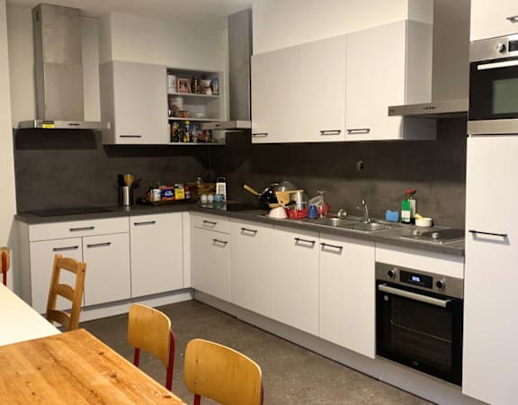 A modern kitchen with white cabinets and a wooden table.