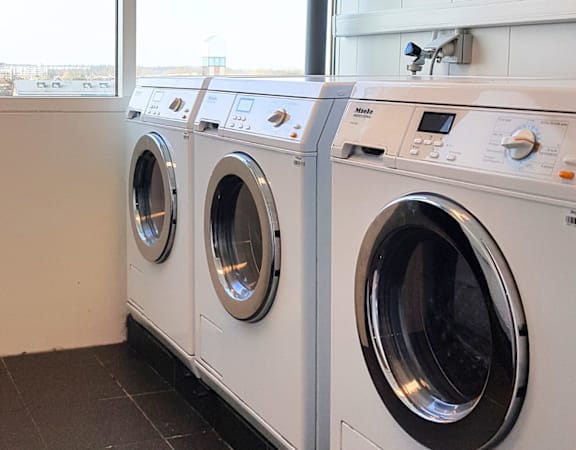 A row of white front load washing machines in a laundromat.