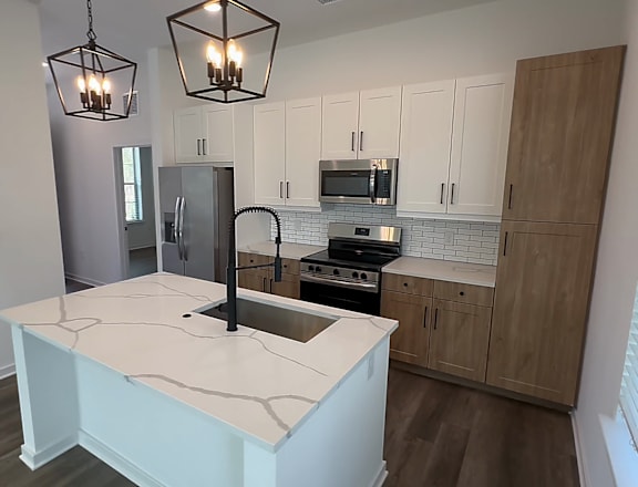 A kitchen with a white island and wooden cabinets.