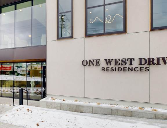 A building with a glass facade and a sign that reads "One West Drive Residences.".