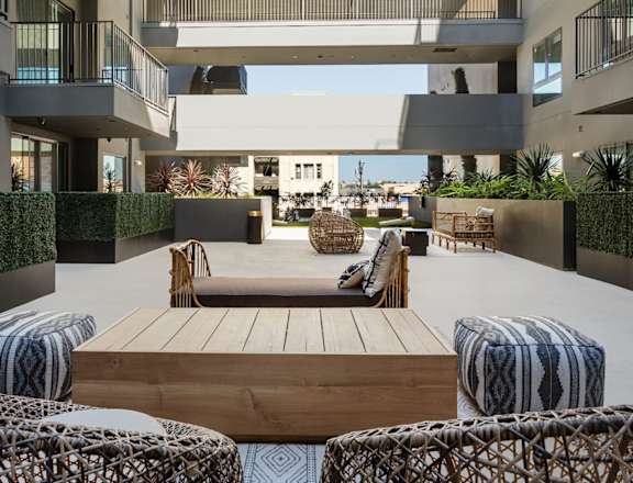 A modern outdoor seating area with a wooden table and woven chairs.